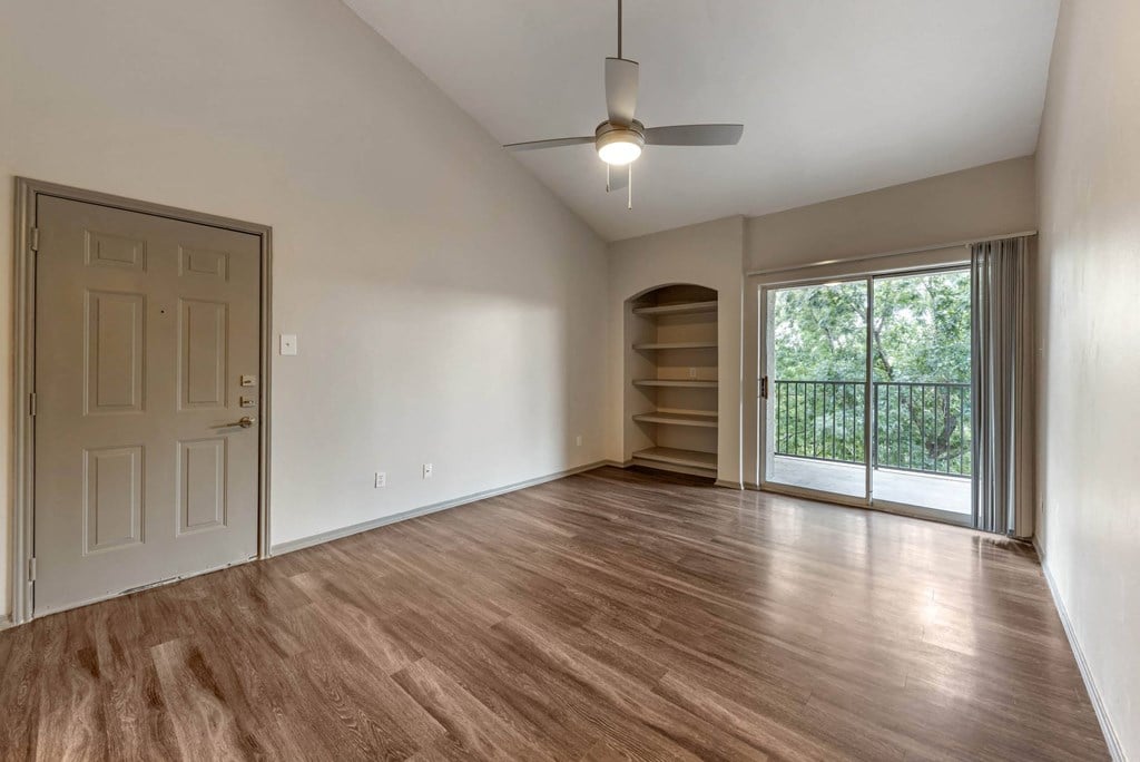 an empty living room with wood flooring and a window